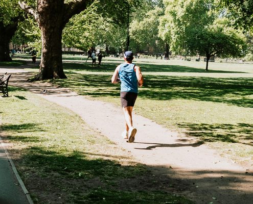 Coureur en camisole bleue sur un sentier de parc ombrag&eacute;